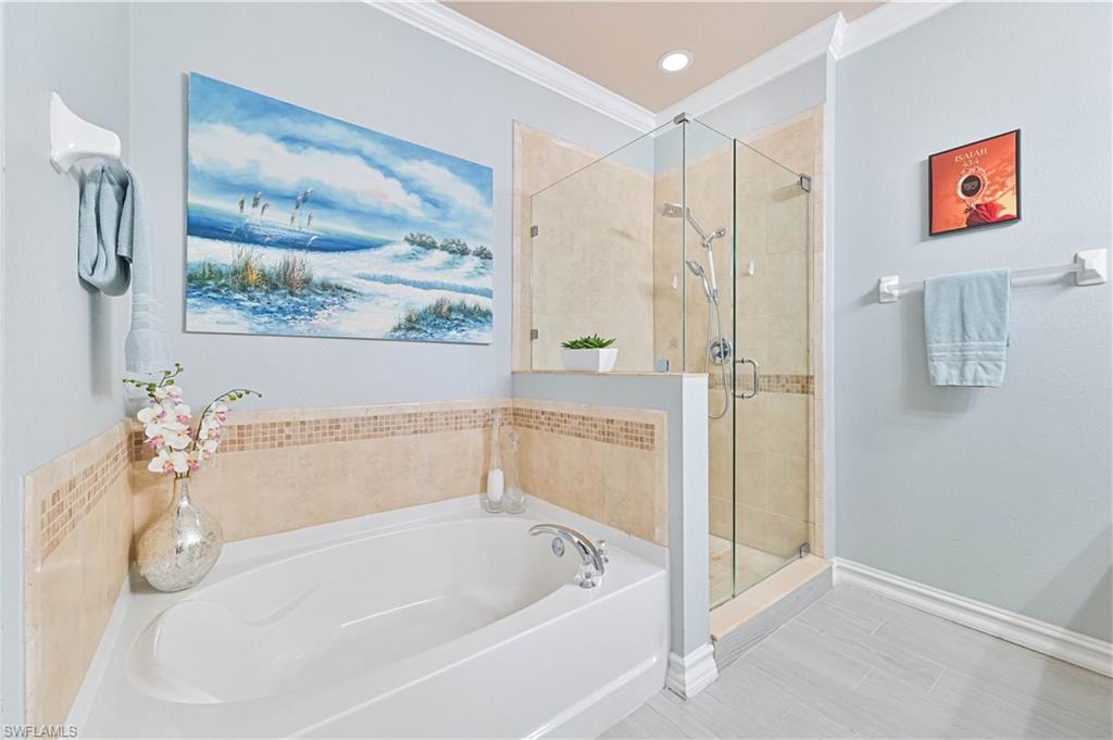 Full bathroom featuring a bath, a shower stall, crown molding, and recessed lighting