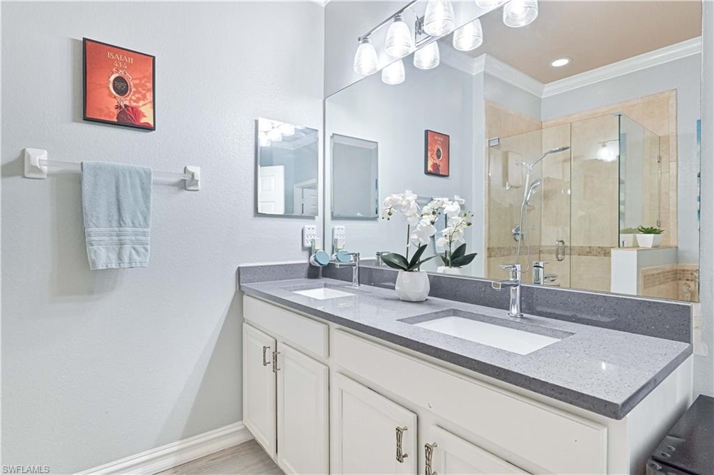 Bathroom with a stall shower, double vanity, ornamental molding, and recessed lighting