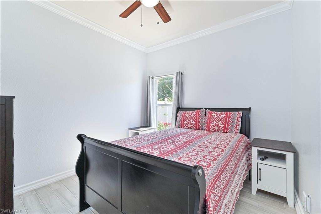Bedroom with crown molding, light wood-style flooring, and ceiling fan