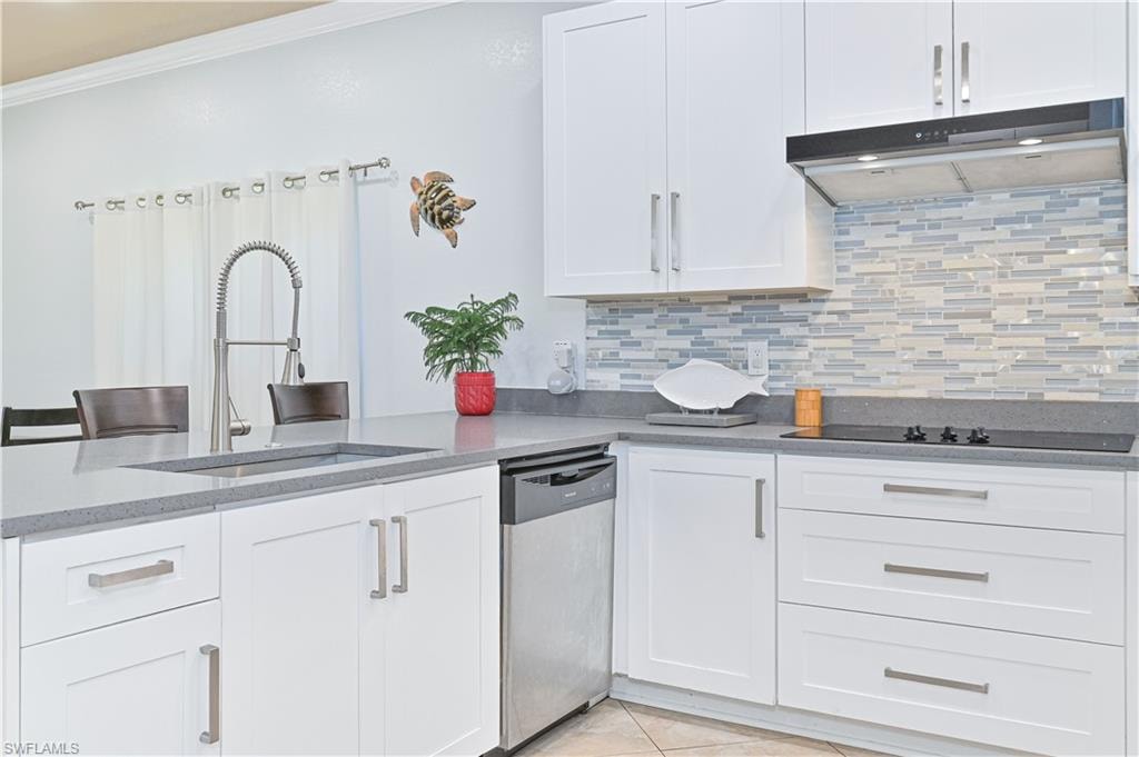 Kitchen featuring white cabinets, stainless steel dishwasher, dark stone countertops, tasteful backsplash, and crown molding