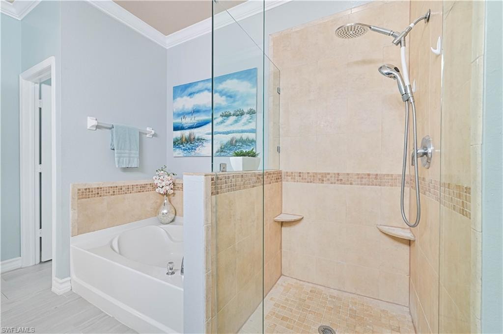 Full bathroom with a stall shower, a garden tub, and crown molding