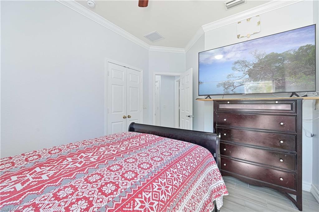 Bedroom with crown molding, a ceiling fan, wood tiled floors, and a closet