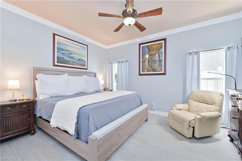Bedroom with crown molding, ceiling fan, and light wood-type flooring