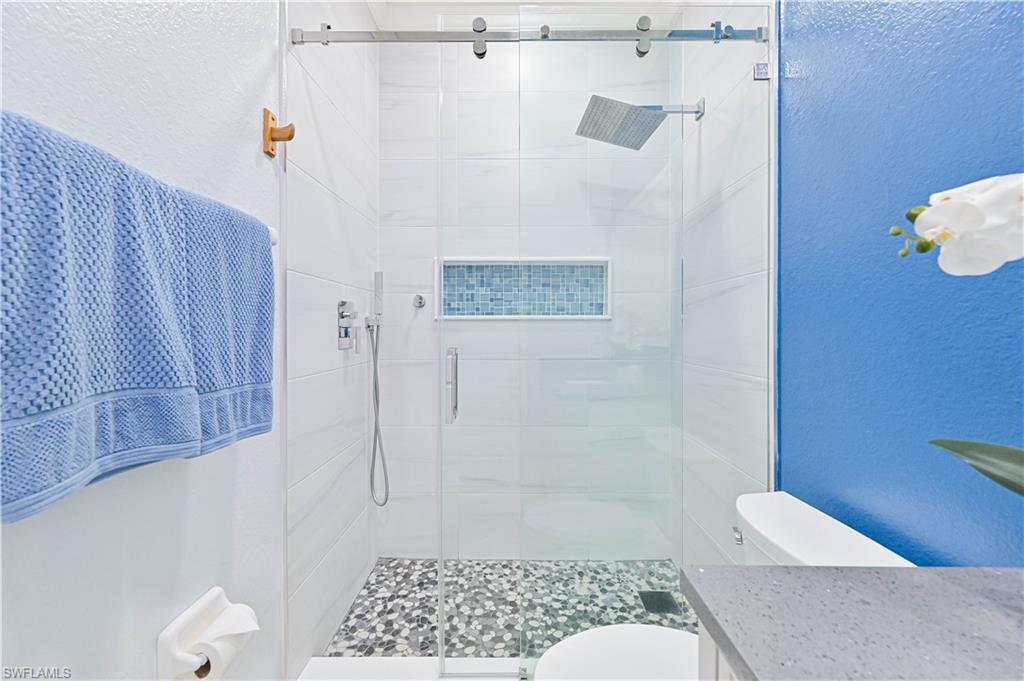Full bath featuring a textured wall, a stall shower, and vanity