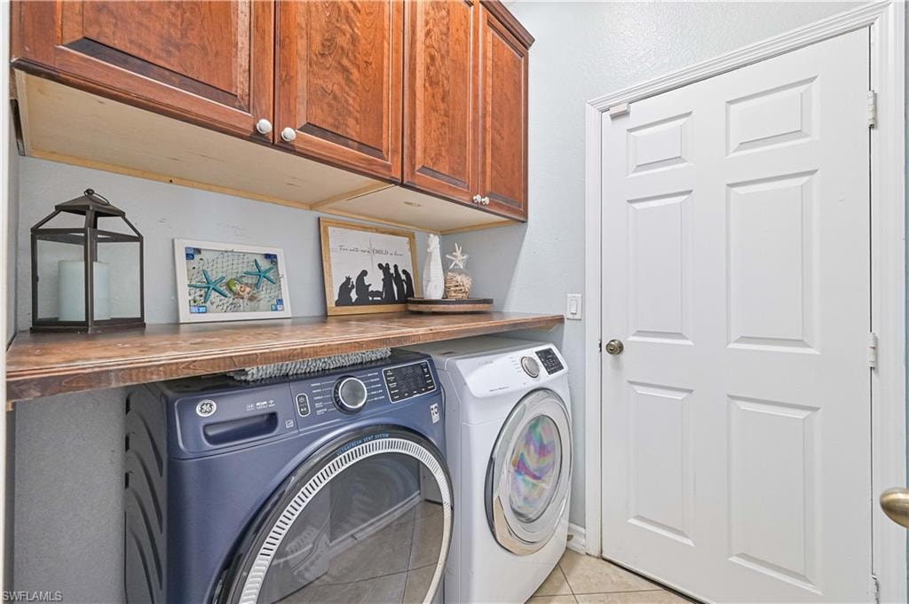 Laundry area featuring cabinet space, independent washer and dryer, and light tile patterned floors
