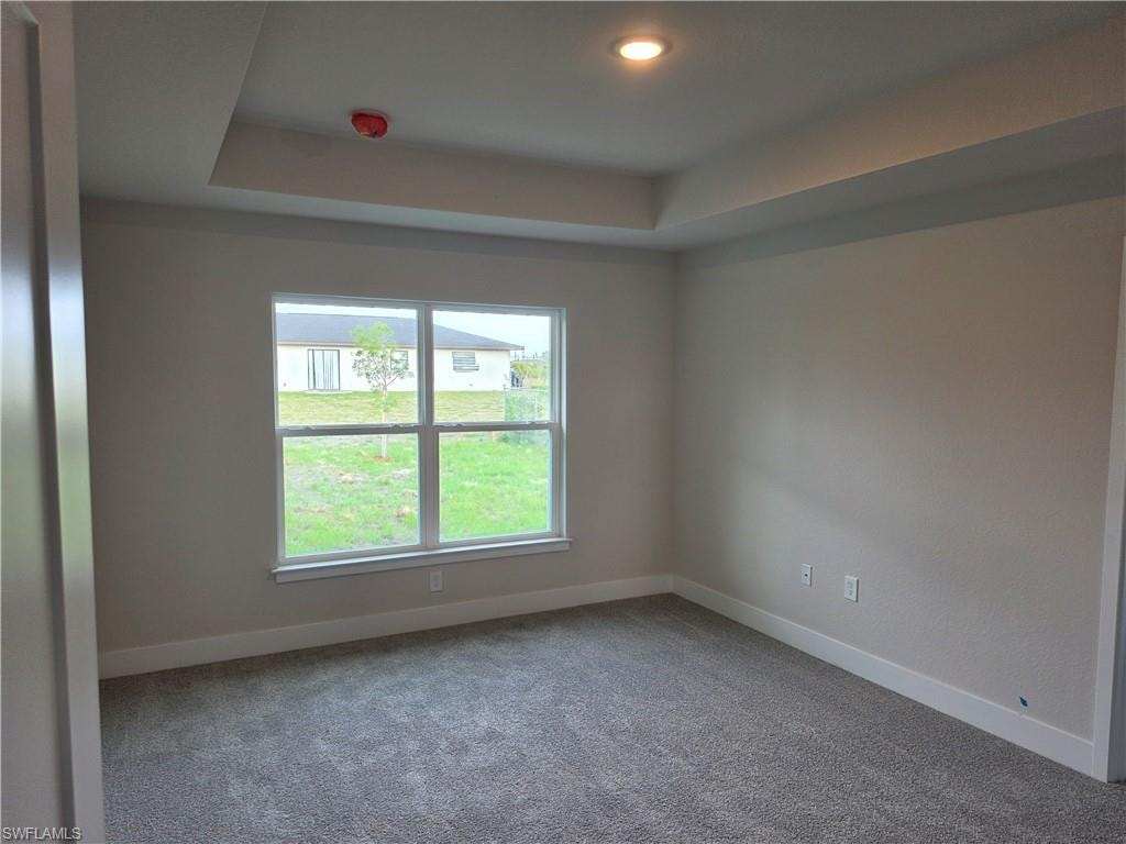 Recessed ceiling with an integrated light fixture, light gray wall paint, white trim, and gray carpet flooring
