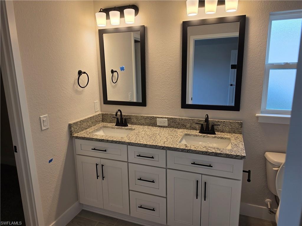 Dual vanity with granite countertop, integrated sinks, and matte black fixtures