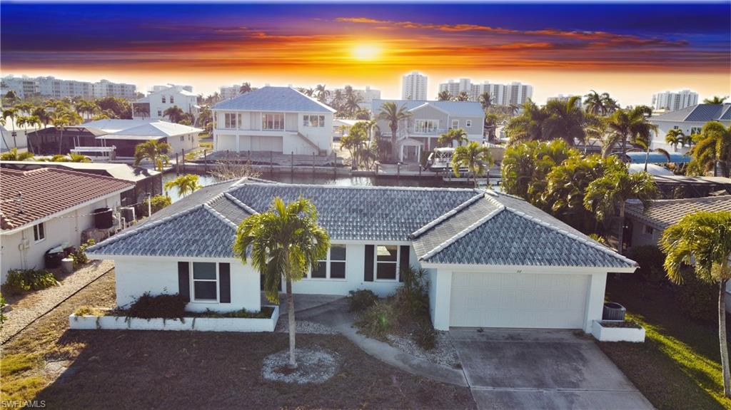 View of front facade featuring a tiled roof, stucco siding, an attached garage, concrete driveway, and a city view