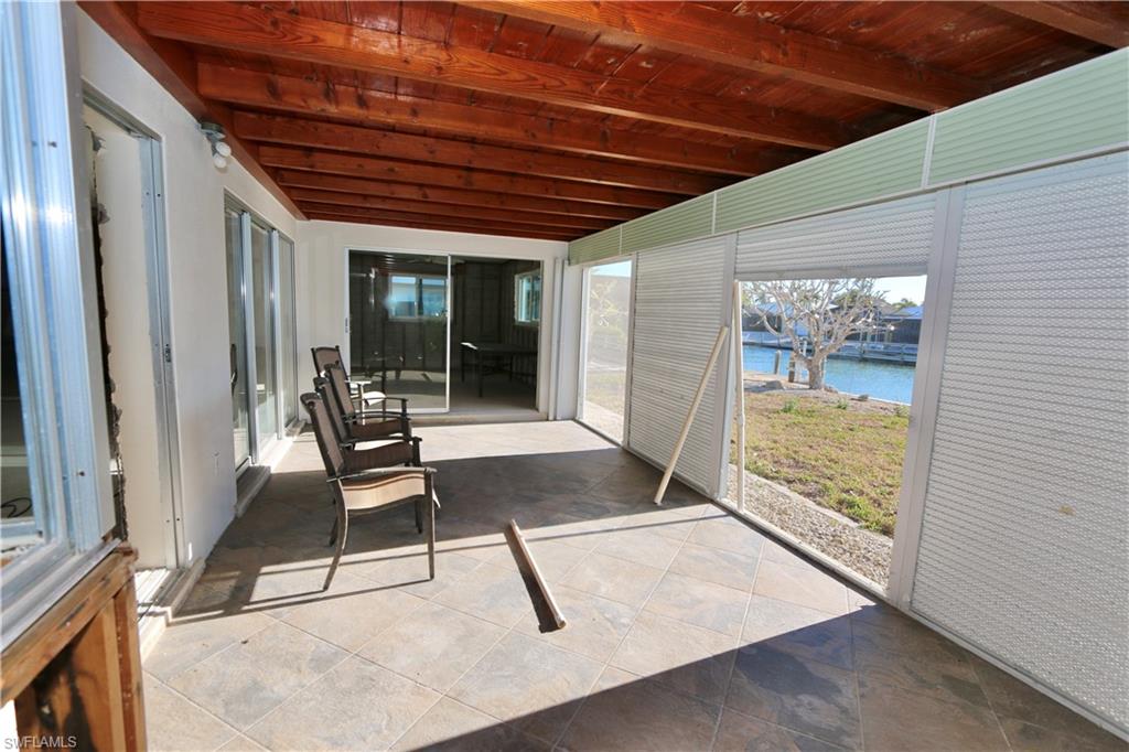 Unfurnished sunroom with a patio, a water view, and a wooden ceiling with exposed beams