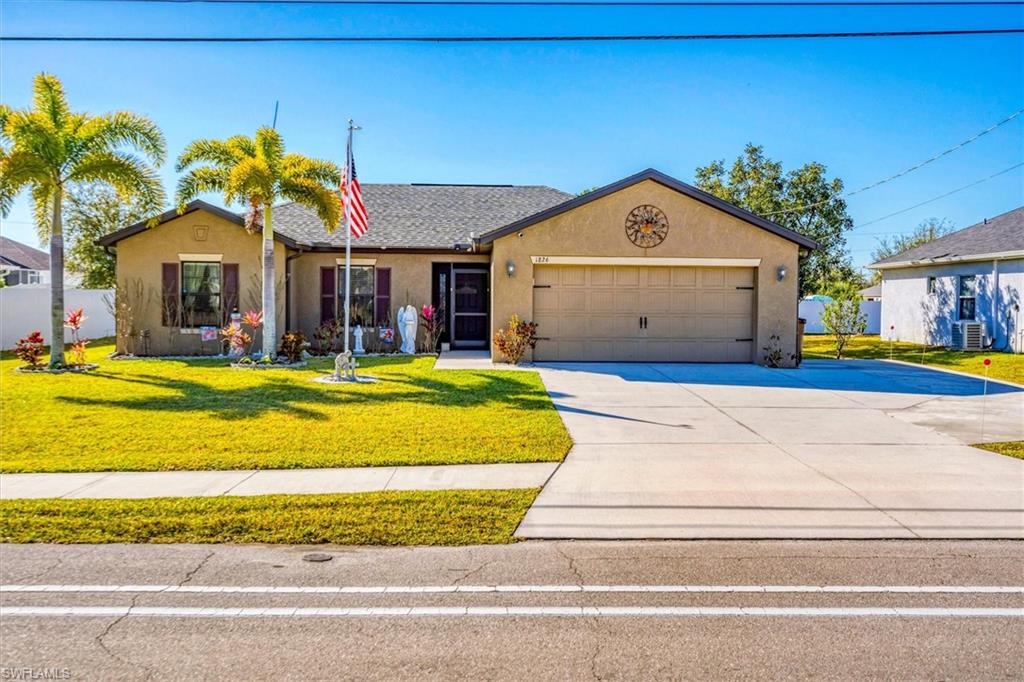 Single story home with a front lawn, stucco siding, concrete driveway, and a garage