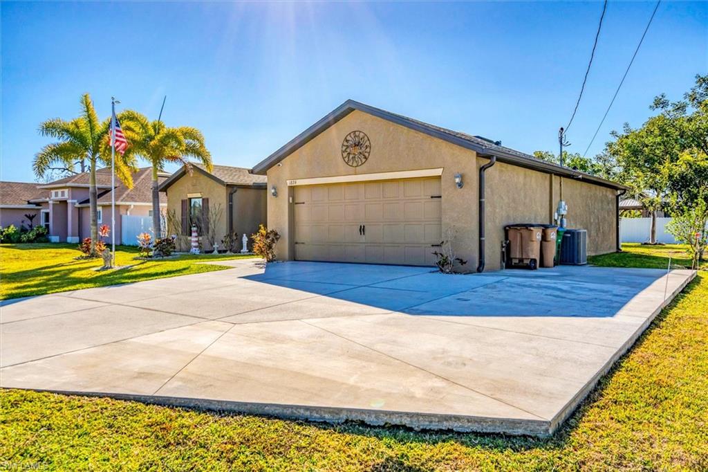 Ranch-style home with a front lawn, stucco siding, driveway, and an attached garage