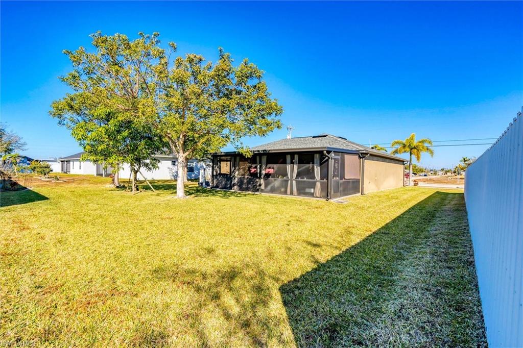 Rear view of property featuring a sunroom and a lawn