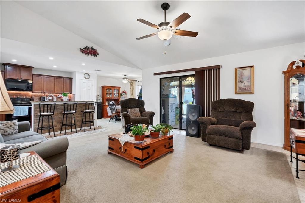 Living area with vaulted ceiling, light carpet, recessed lighting, and a ceiling fan