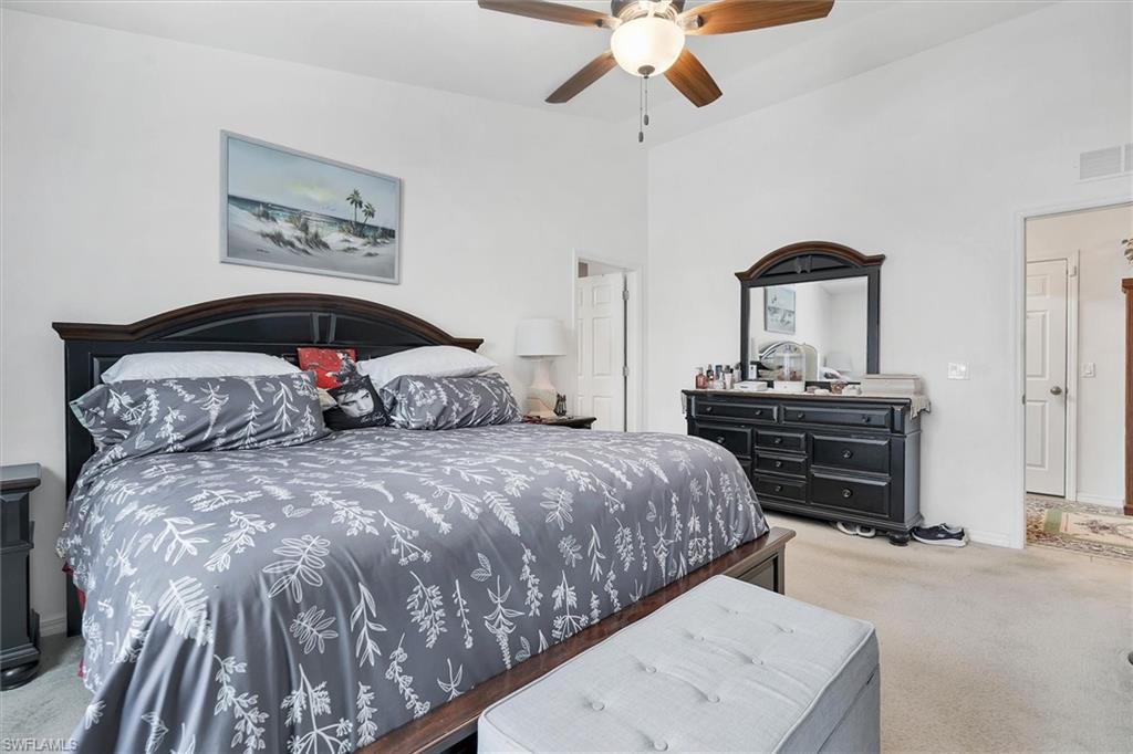 Bedroom featuring light colored carpet, ceiling fan, and a high ceiling