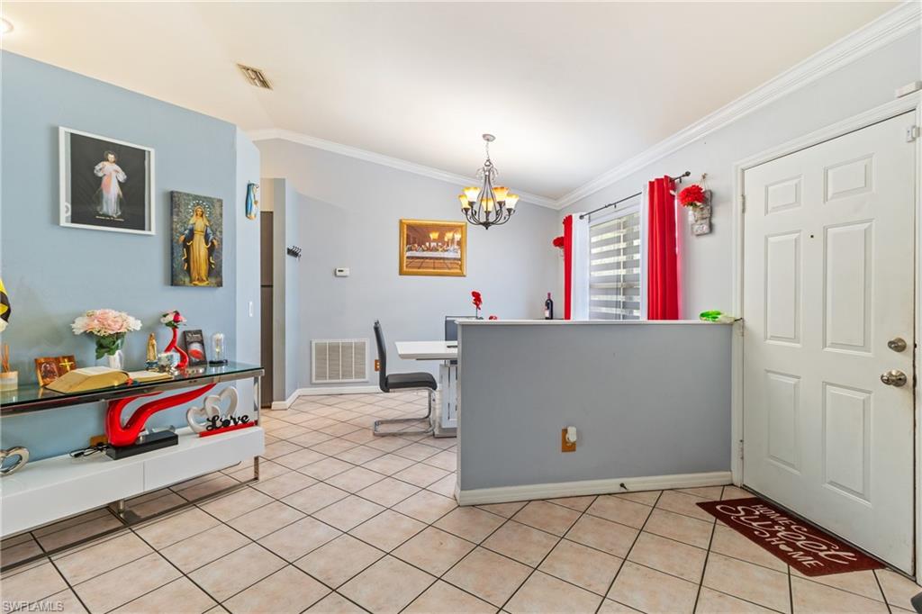 Dining area with crown molding, suspended lighting, and light tile patterned floors