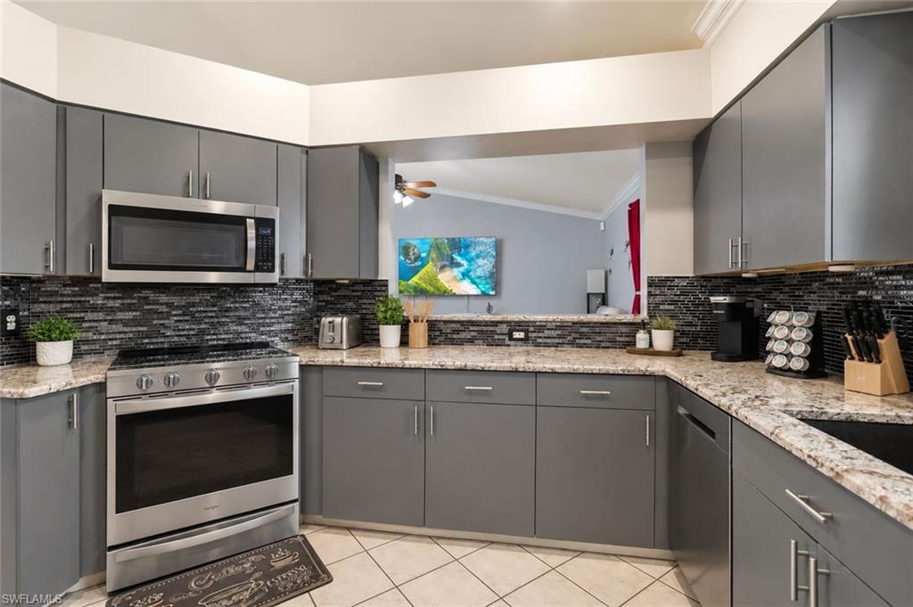 Kitchen featuring gray cabinets, ornamental molding, dishwasher, and light tile patterned floors