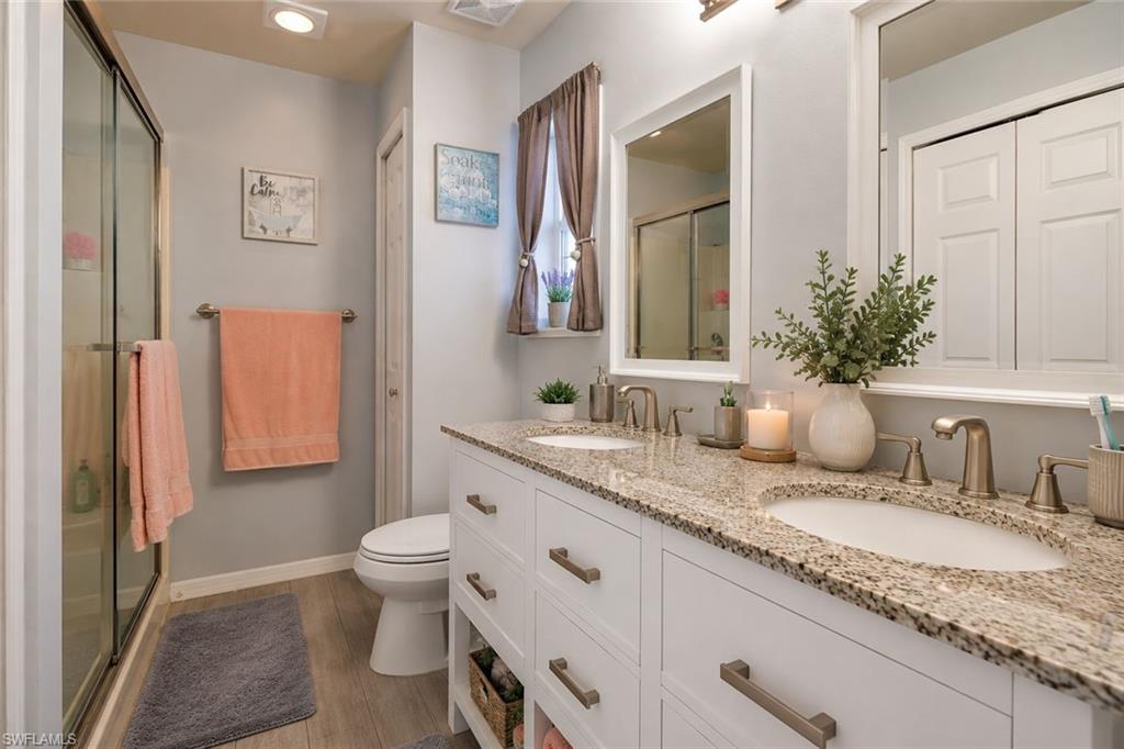 Bedroom with wood finish floors, a ceiling fan, and ensuite bathroom