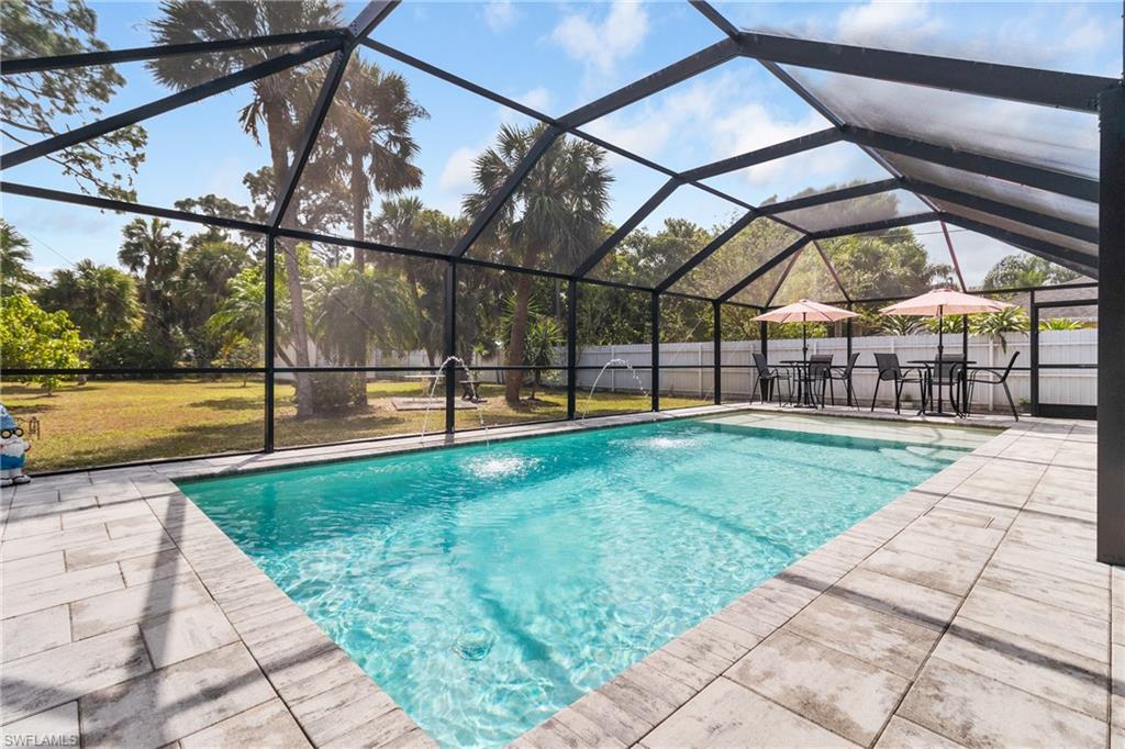 View of pool featuring a lanai, a fenced backyard, a sunroom, and patio surround