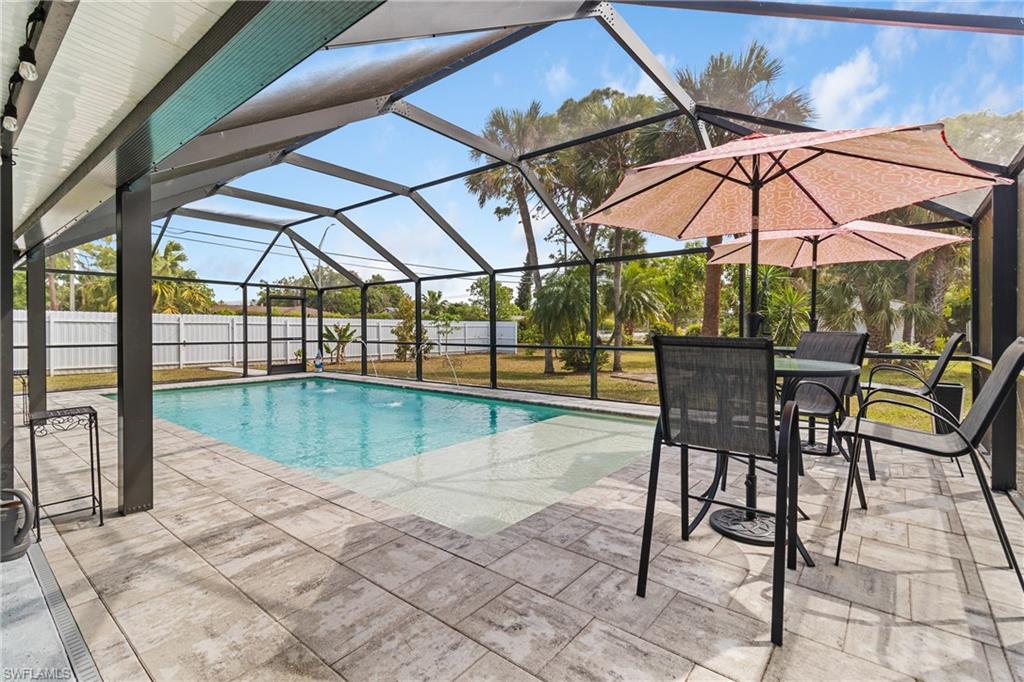 View of pool with a sunroom, a lanai, patio surround, outdoor dining space, and a fenced backyard