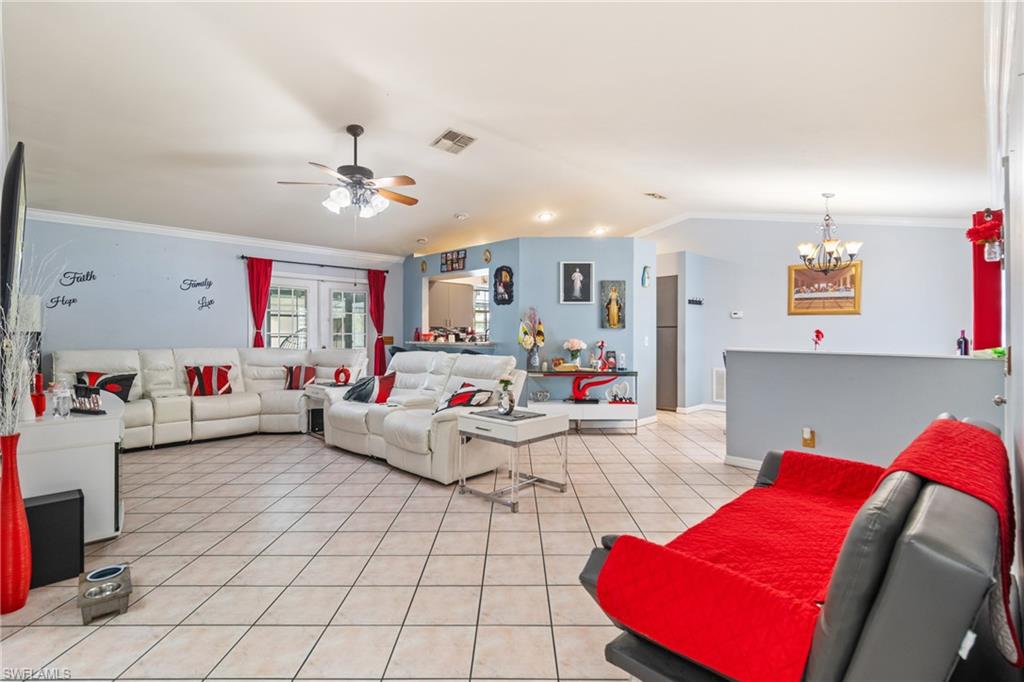 Kitchen featuring crown molding, stainless steel refrigerator with ice dispenser, a kitchen bar, white cabinetry, and light stone counters