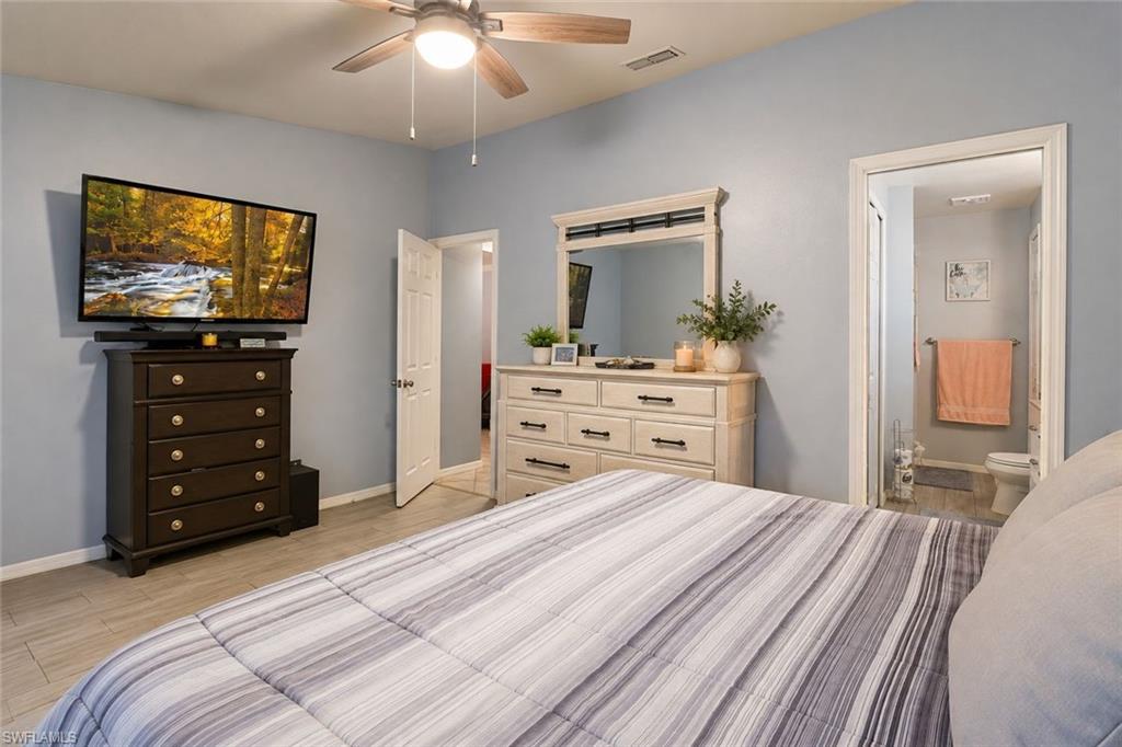 Bedroom featuring lofted ceiling, a ceiling fan, and connected bathroom