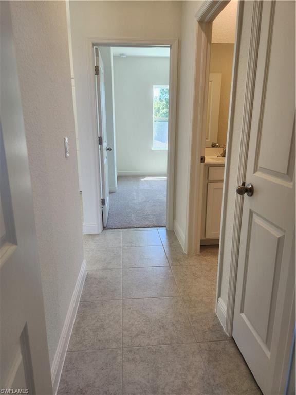Hall with light tile patterned flooring and a textured wall