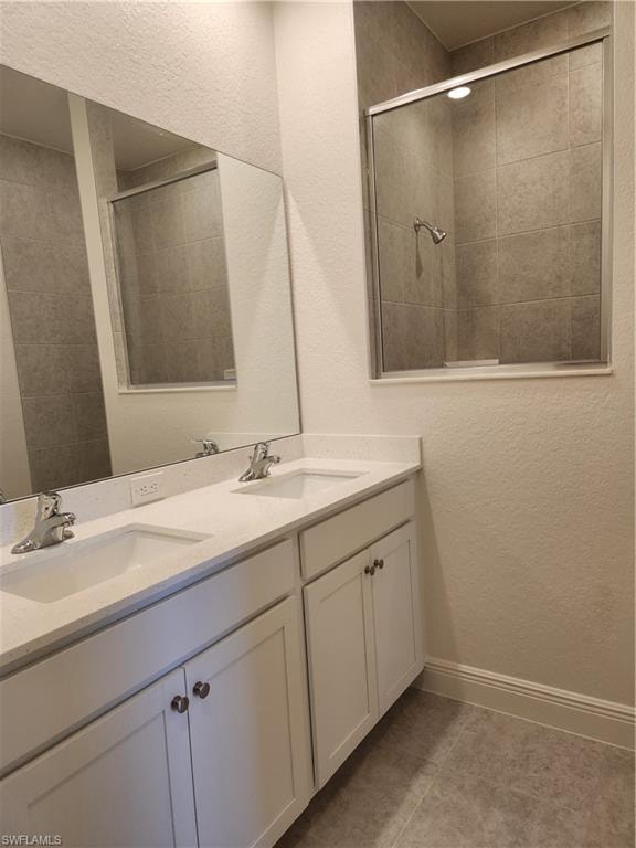 Bathroom featuring a textured wall, double vanity, and light tile patterned flooring