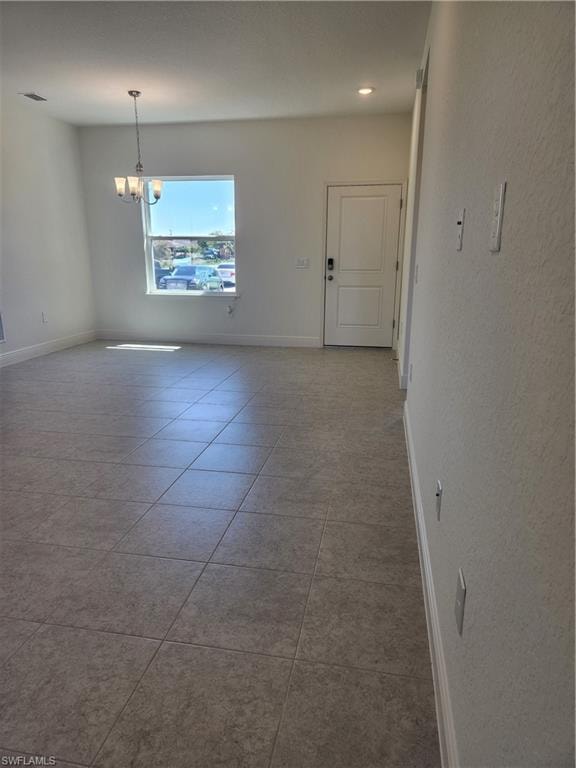Empty room with light tile patterned floors, hanging lights, and a textured wall