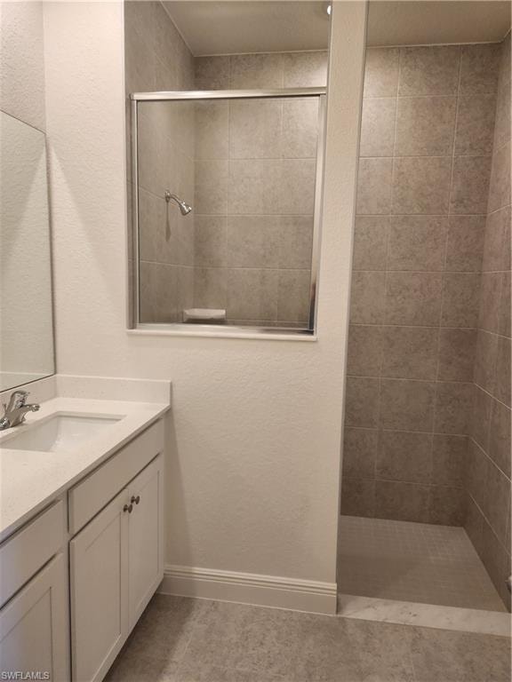 Bathroom featuring a stall shower, a textured wall, vanity, and light tile patterned flooring