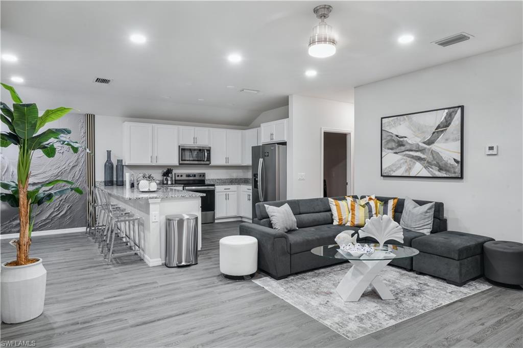 Living room featuring light wood-style flooring, recessed lighting, and lofted ceiling