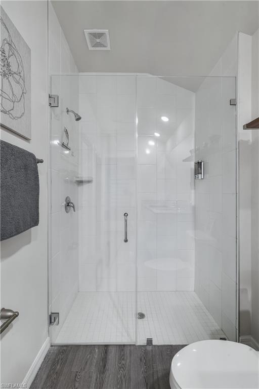 Full bath with a shower stall and wood finished floors