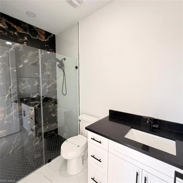 Full bathroom featuring vanity, a marble finish shower, and marble finish floors