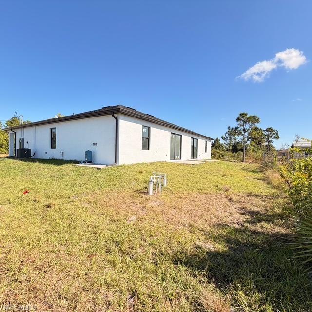 Rear view of property with stucco siding and a yard