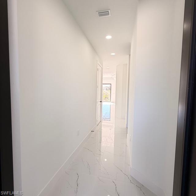 Hallway with recessed lighting and light marble finish floors