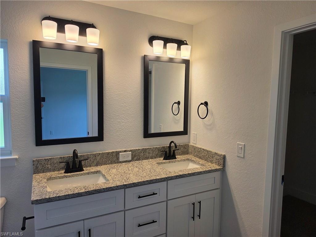 Double vanity featuring light-toned countertops, two undermount sinks, and matte black faucets