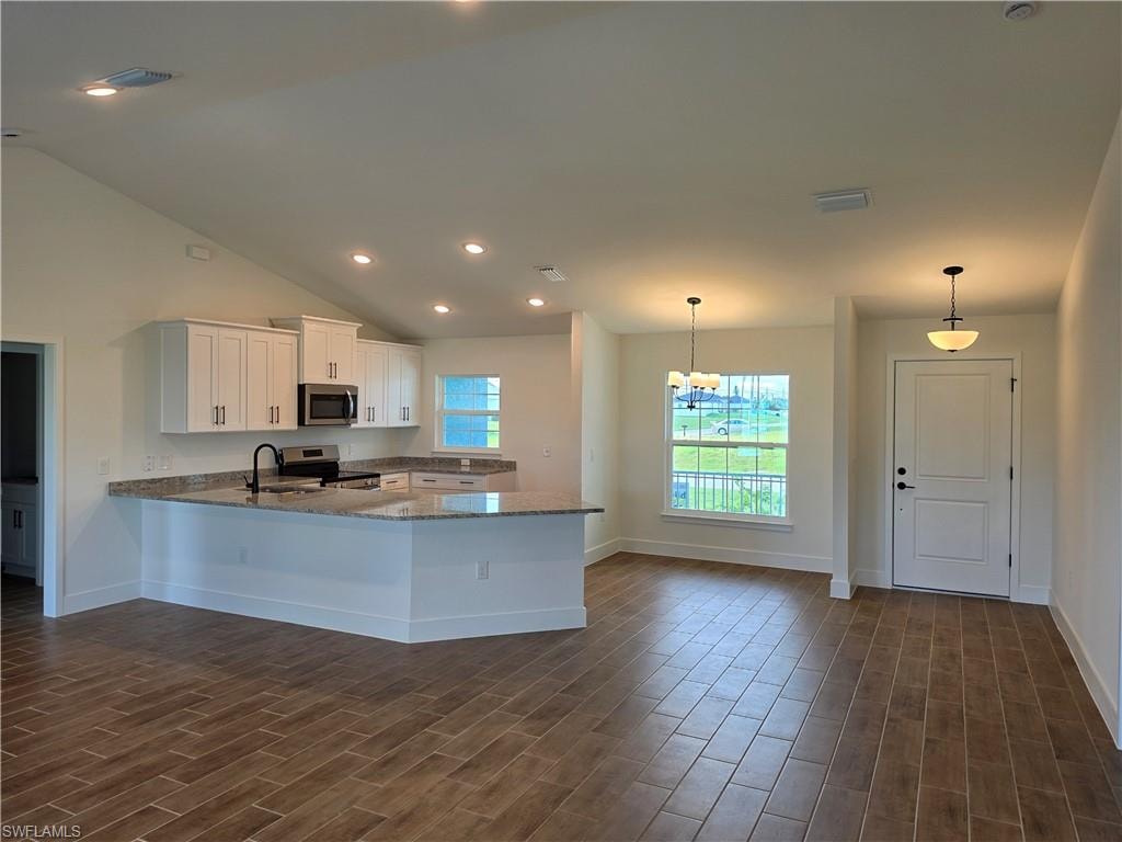 Open-concept living space featuring wood-finish tile flooring, a vaulted ceiling, and recessed lighting