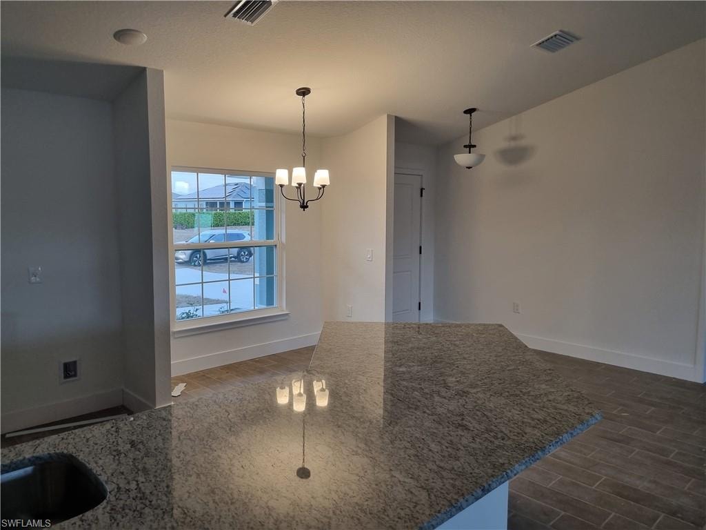 Unfurnished dining area with a chandelier and wood finish floors