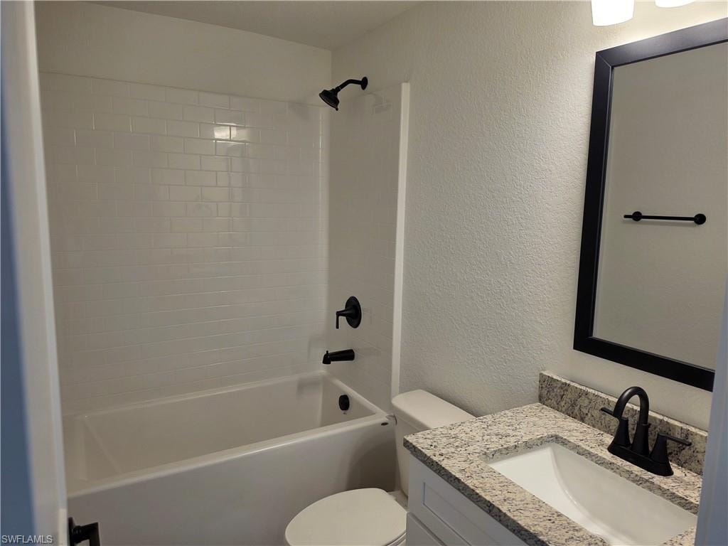 Bathroom featuring a subway-tiled shower surround, a white bathtub, and matte black fixtures