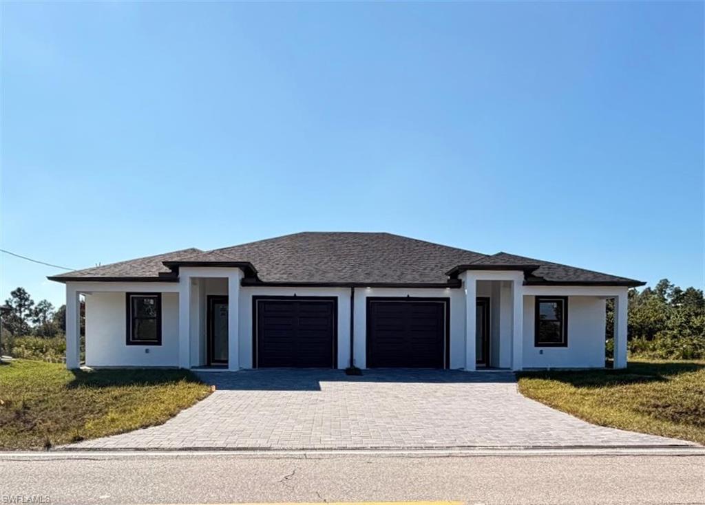 Prairie-style house featuring a front lawn, decorative driveway, stucco siding, a garage, and roof with shingles