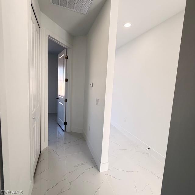 Corridor with light marble finish flooring and recessed lighting