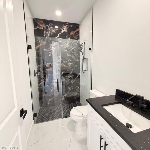 Bathroom featuring a marble finish shower, vanity, light marble finish flooring, and recessed lighting