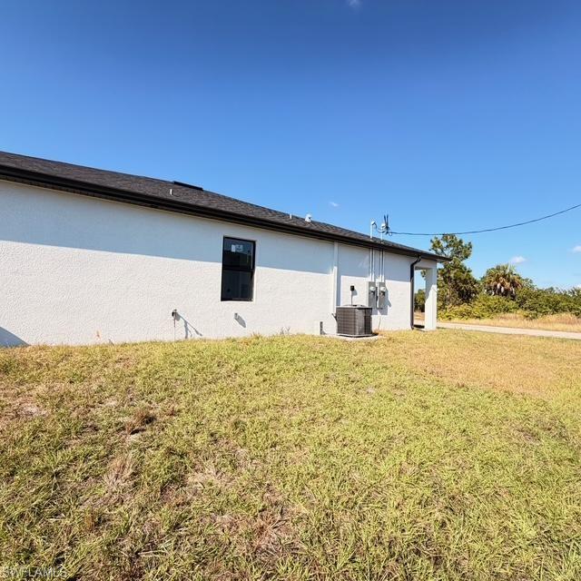 View of side of home featuring a lawn and stucco siding