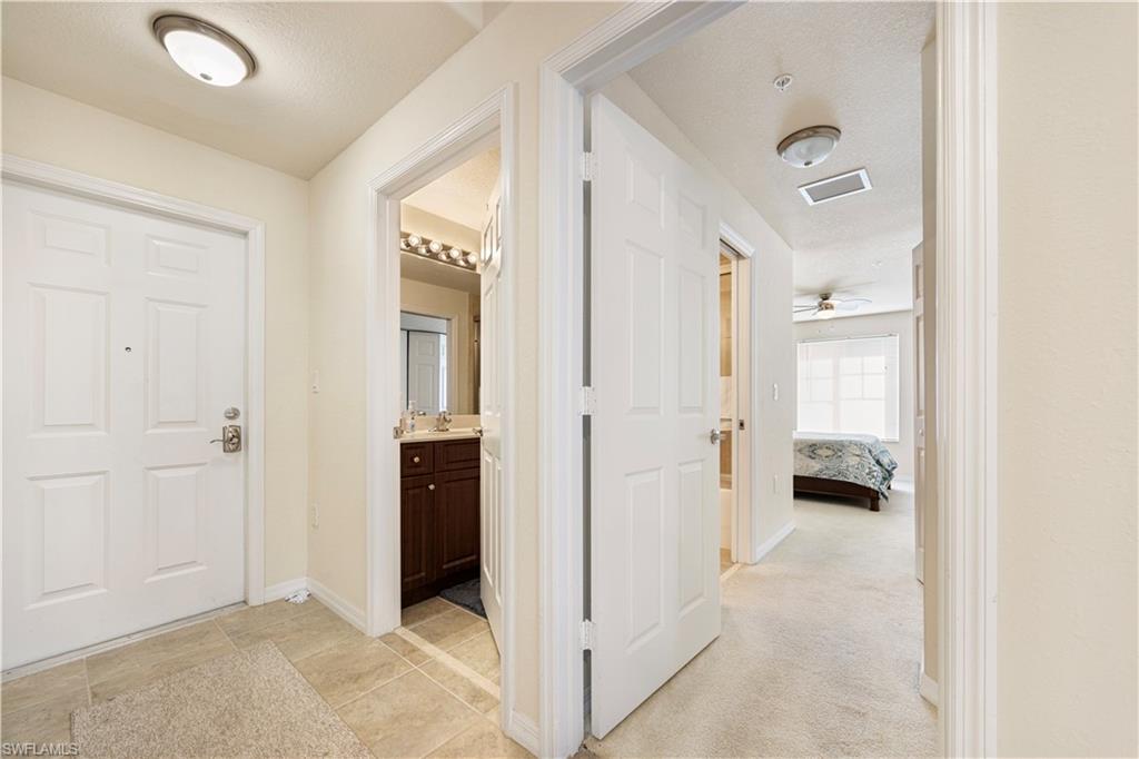 Hallway featuring light carpet and a textured ceiling