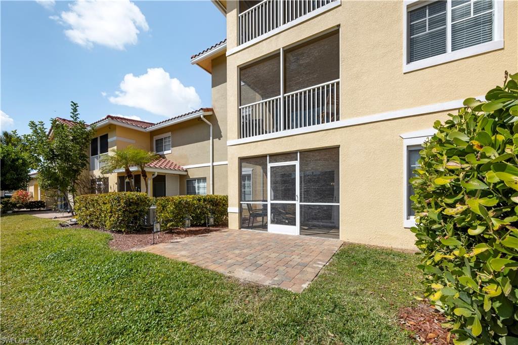 Rear view of property with a sunroom, stucco siding, a tiled roof, a yard, and a patio area