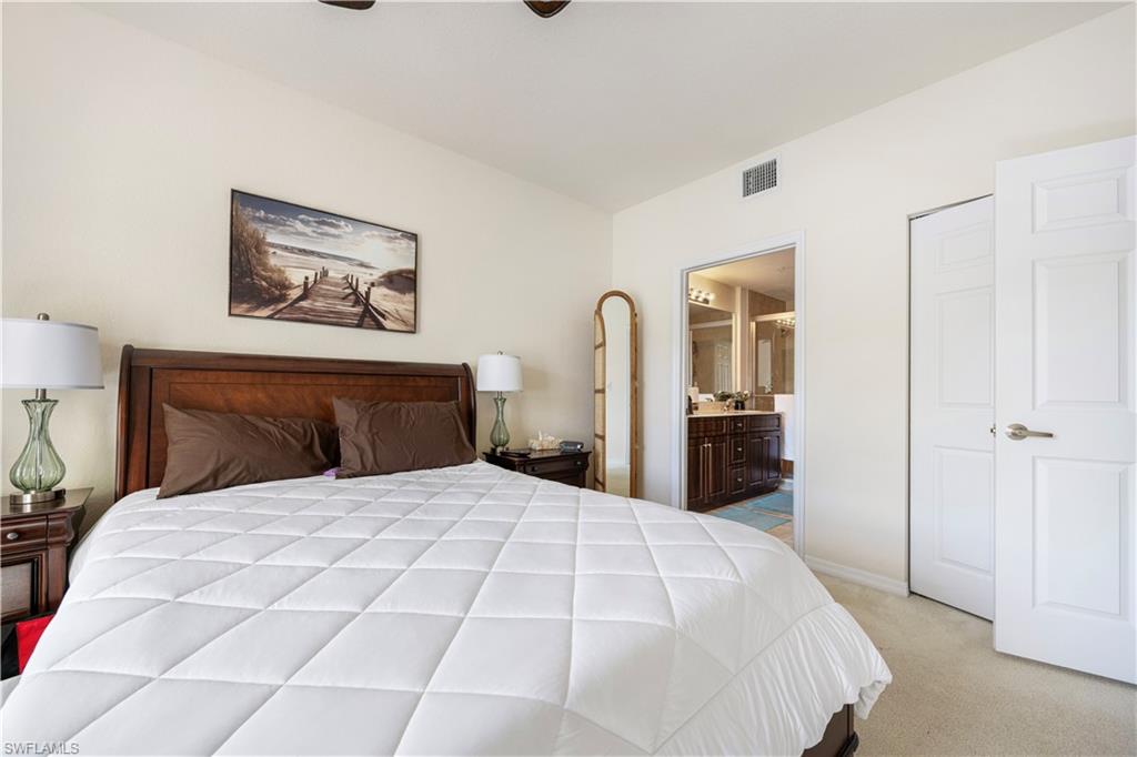 Bedroom with light colored carpet, ensuite bathroom, and a ceiling fan