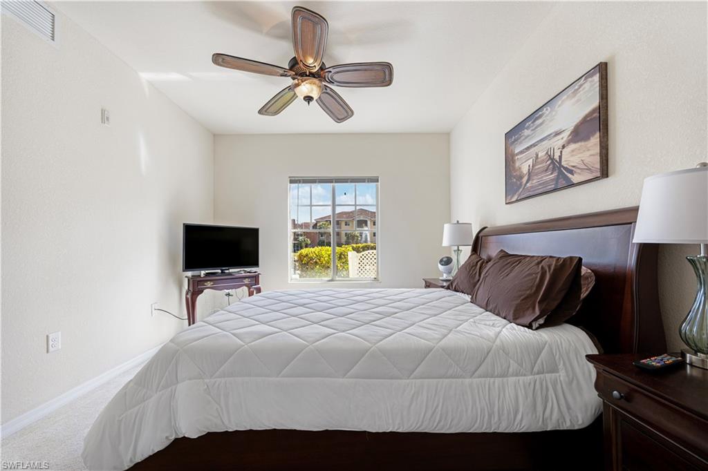 Carpeted bedroom featuring ceiling fan and a textured wall