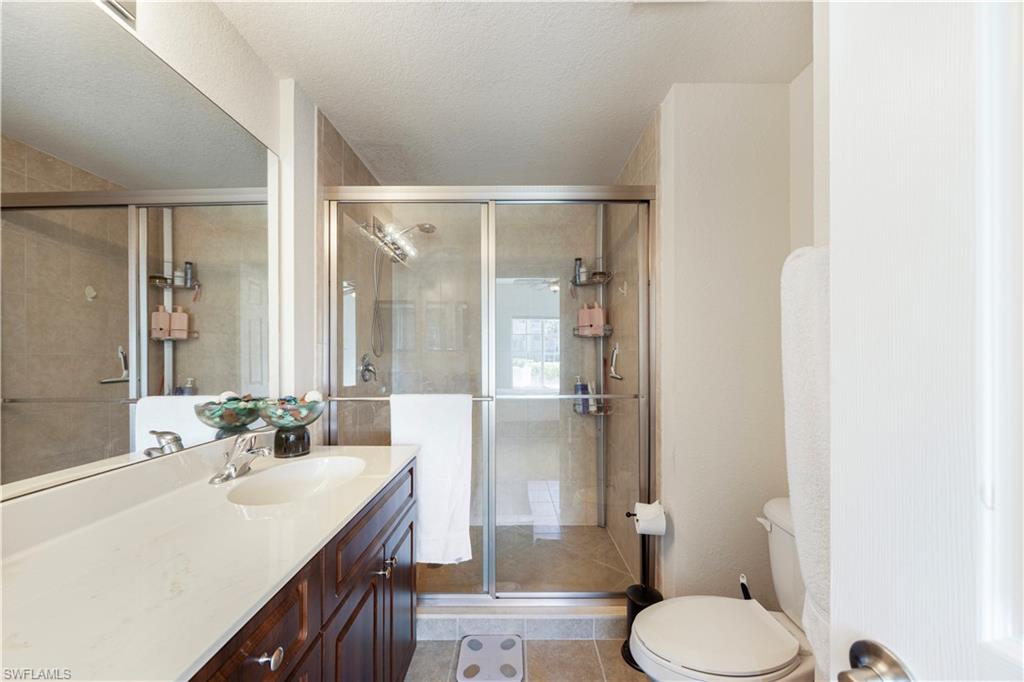 Full bathroom with vanity, a stall shower, light tile patterned floors, and a textured ceiling