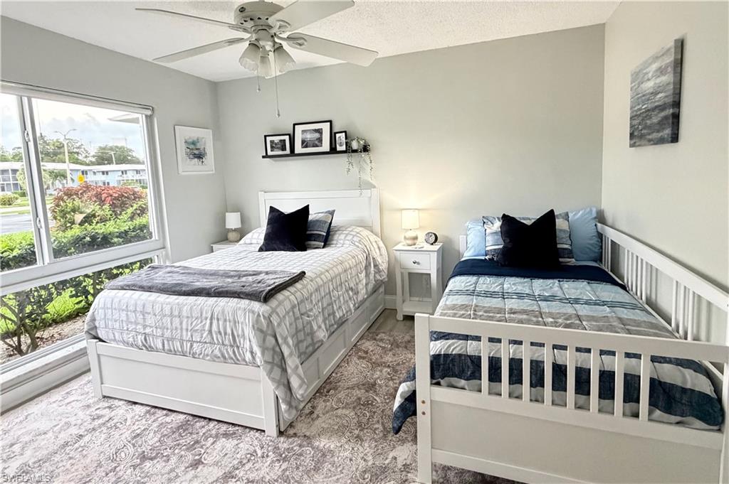 Full bed and twin day bed with large picture window and ceiling fan.