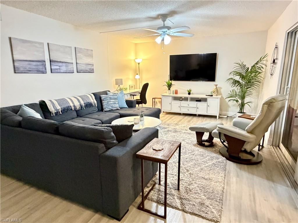 Great room area with TV, desk, luxury vinyl plank flooring with access to the enclosed lanai and views of the the golf course and water feature.