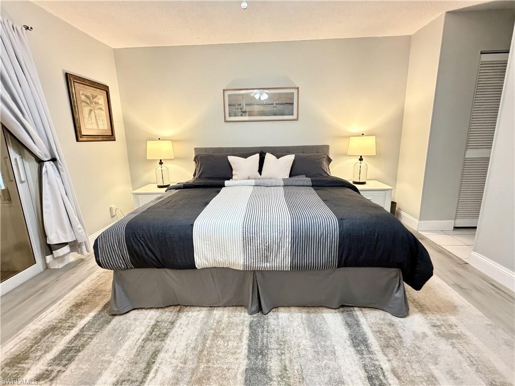 King Bed with luxury vinyl plank flooring, ceiling fan and TV with dresser.